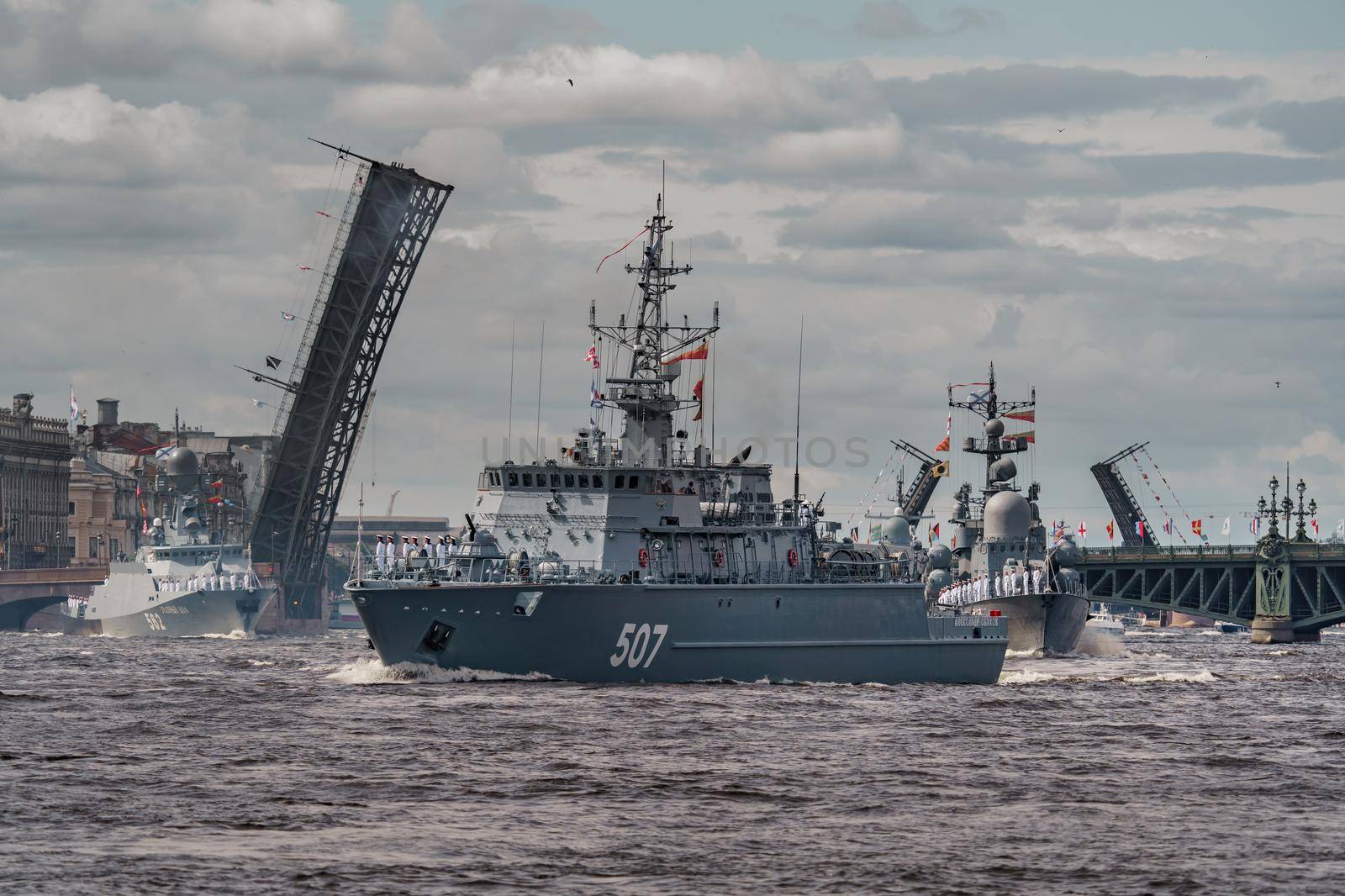 Russia, St. Petersburg, 28 July 2022: A lot of warships goes along the Neva River under open bridges at the time of the rehearsal of the celebration of the day of the Navy in sunny weather. High quality photo