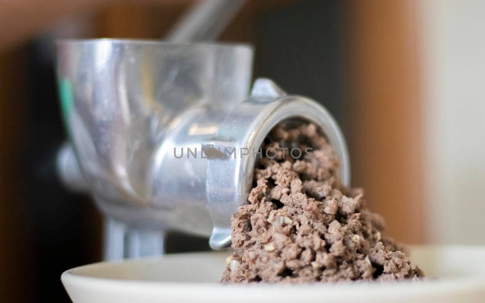 Minced meat in a manual mechanical meat grinder. Fresh boiled meat is ground with an old metal meat grinder, close-up in the kitchen
