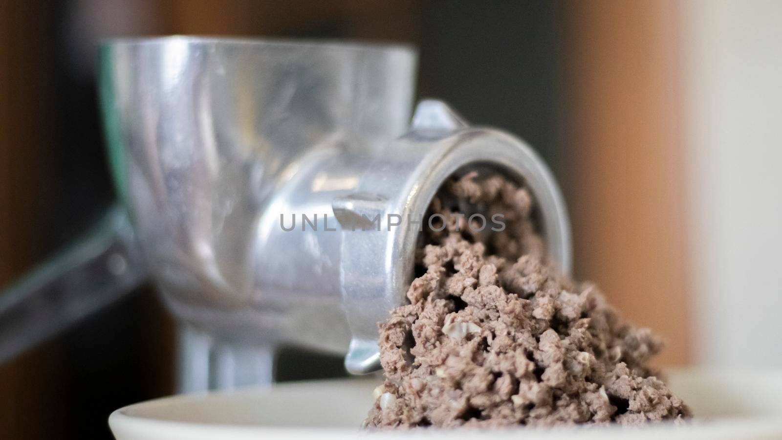 Minced meat in a manual mechanical meat grinder. Fresh boiled meat is ground with an old metal meat grinder, close-up in the kitchen