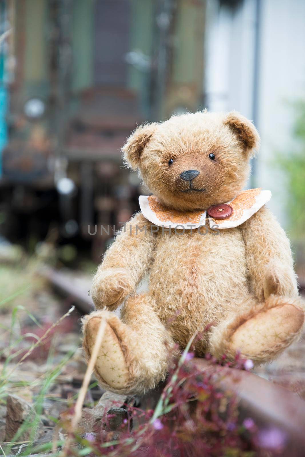 cute brown teddy bear sits alone on empty mini-rails and looks into the distance by KaterinaDalemans