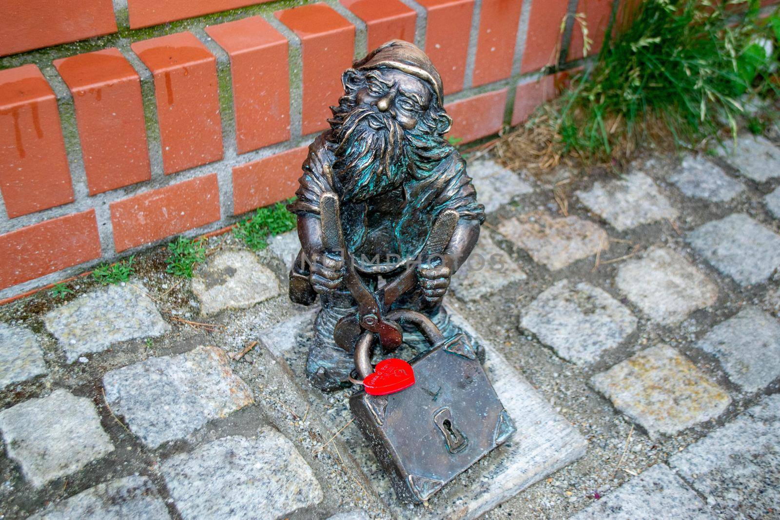 Dwarf gnomes sculpture with magnifying glass in downtown of famous polish city. Wroclaw Houses and streets of the city of Wroclaw. Cityscape. High quality photo