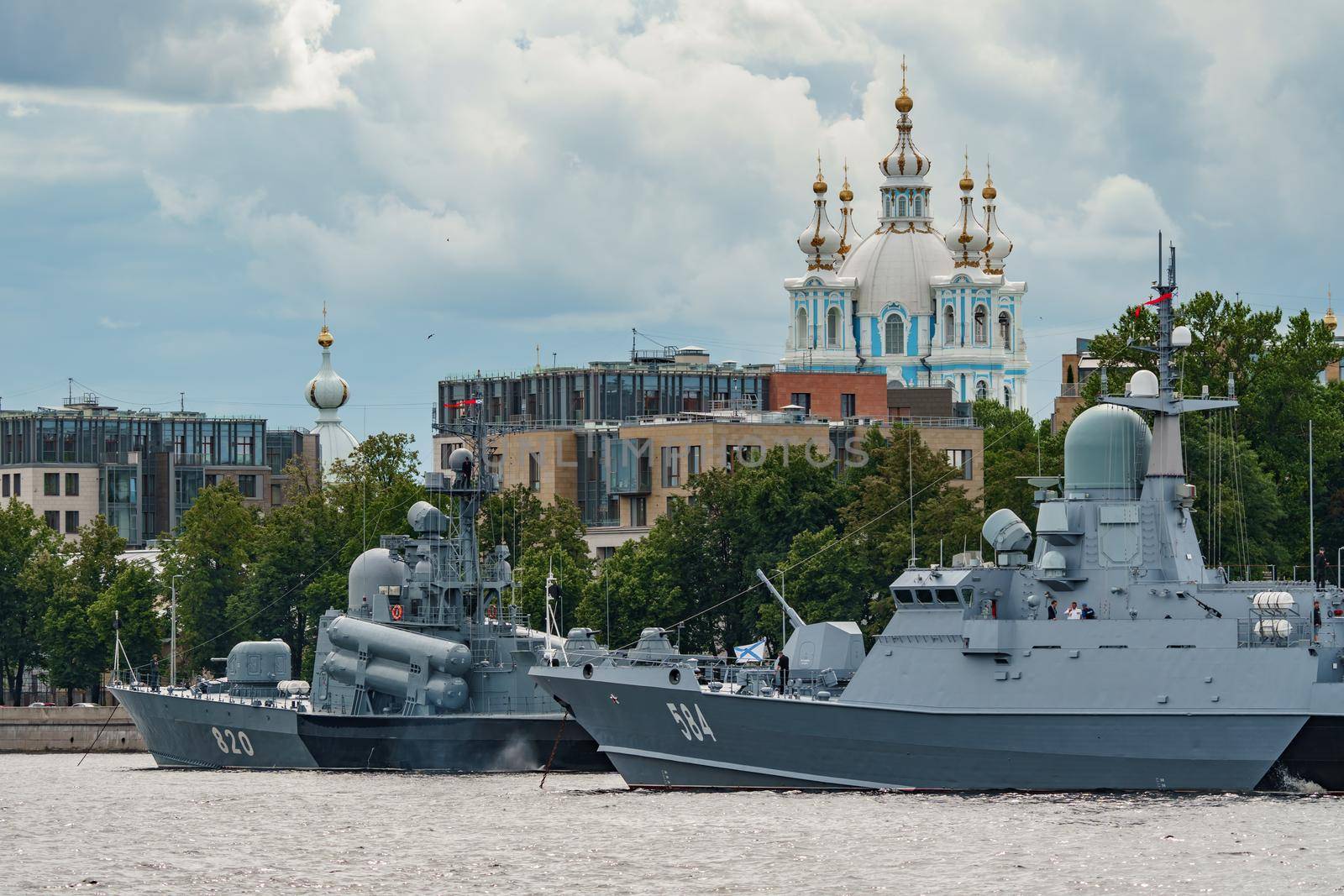 Russia, St. Petersburg, 28 July 2022: A several modern warships anchored at the Neva River embankment during the Navy Day celebrations in sunny weather, sailors on deck in festive uniforms. High quality photo