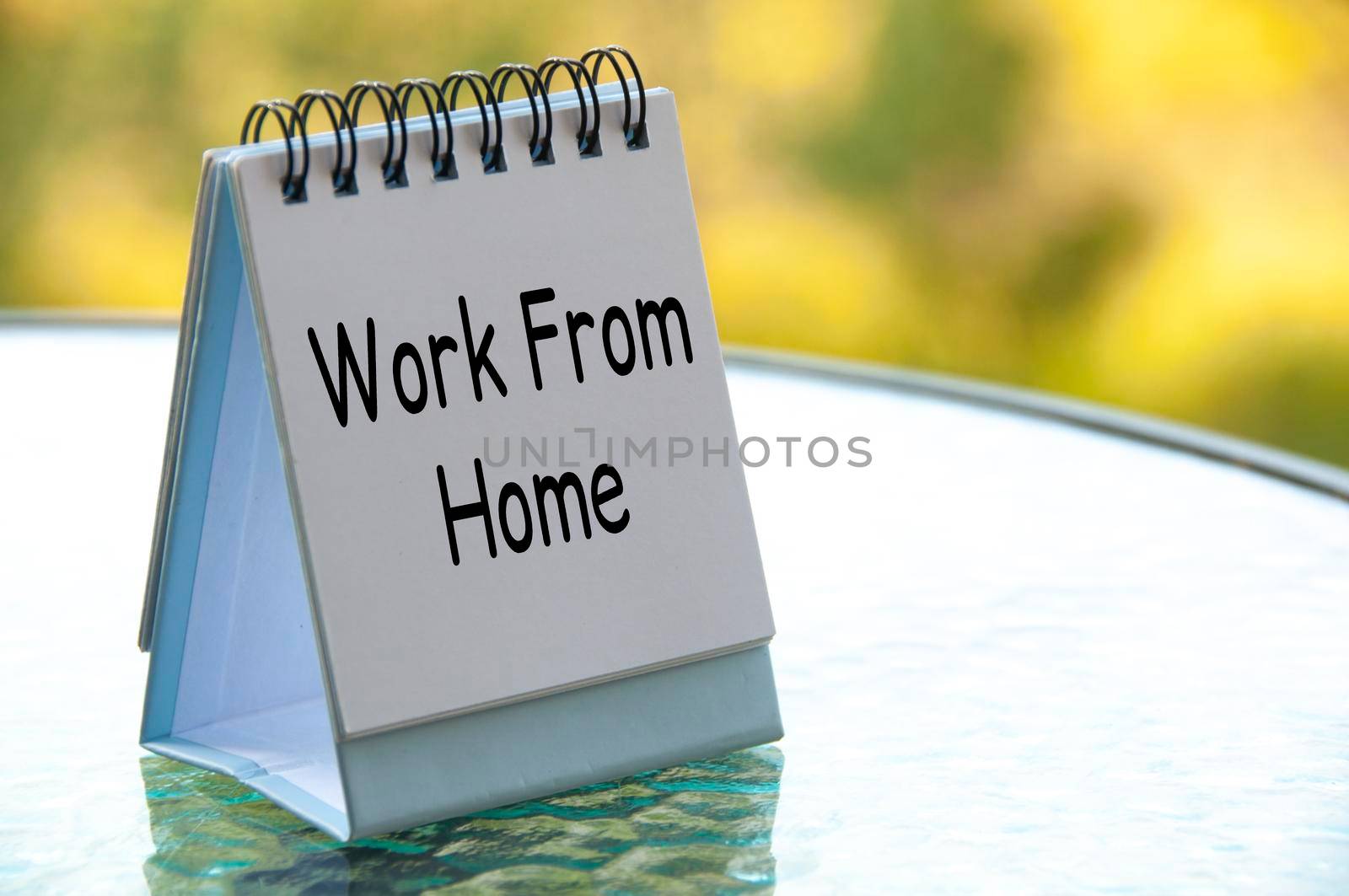 Work from home text on white calendar table with blurred nature background. Work from home concept