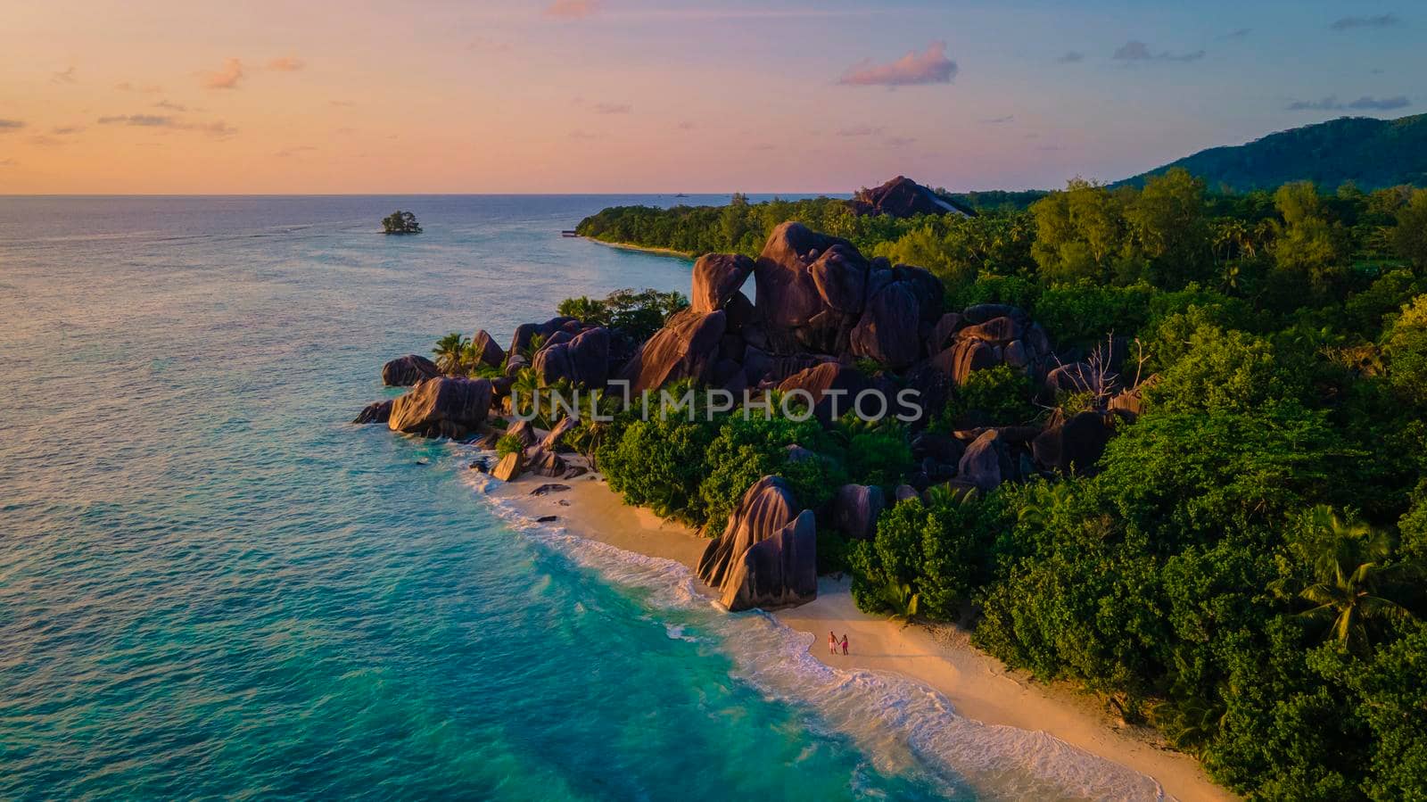 Anse Source d'Argent beach, La Digue Island, Seyshelles, Drone aerial view of La Digue Seychelles bird eye view.of tropical Island, couple men and woman walking at the beach during sunset at a luxury vacation