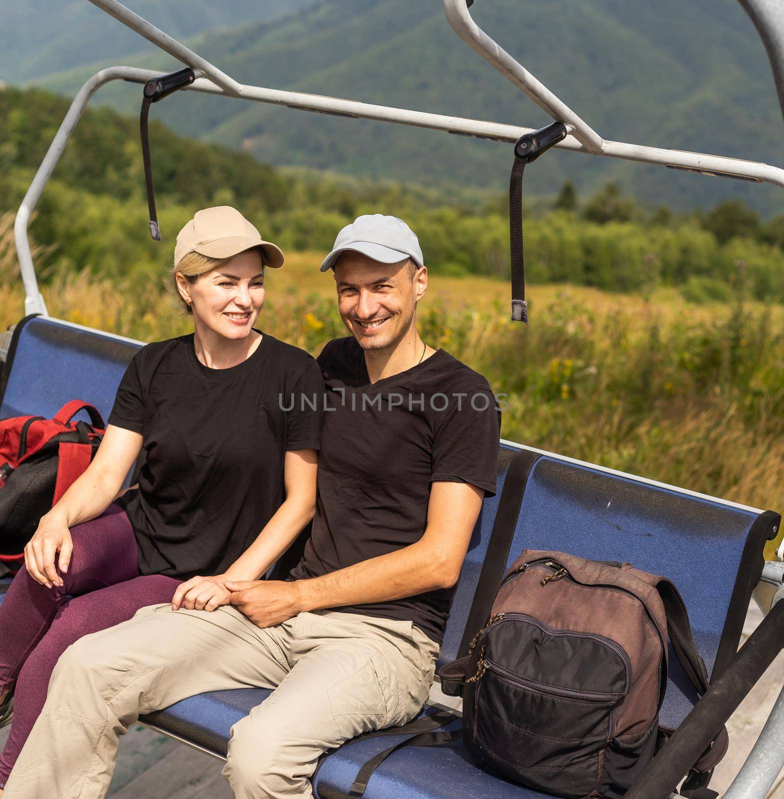 People sit on the ski elevator. View from the back. Summer, green forest. summer family vacation in the mountains. by Andelov13