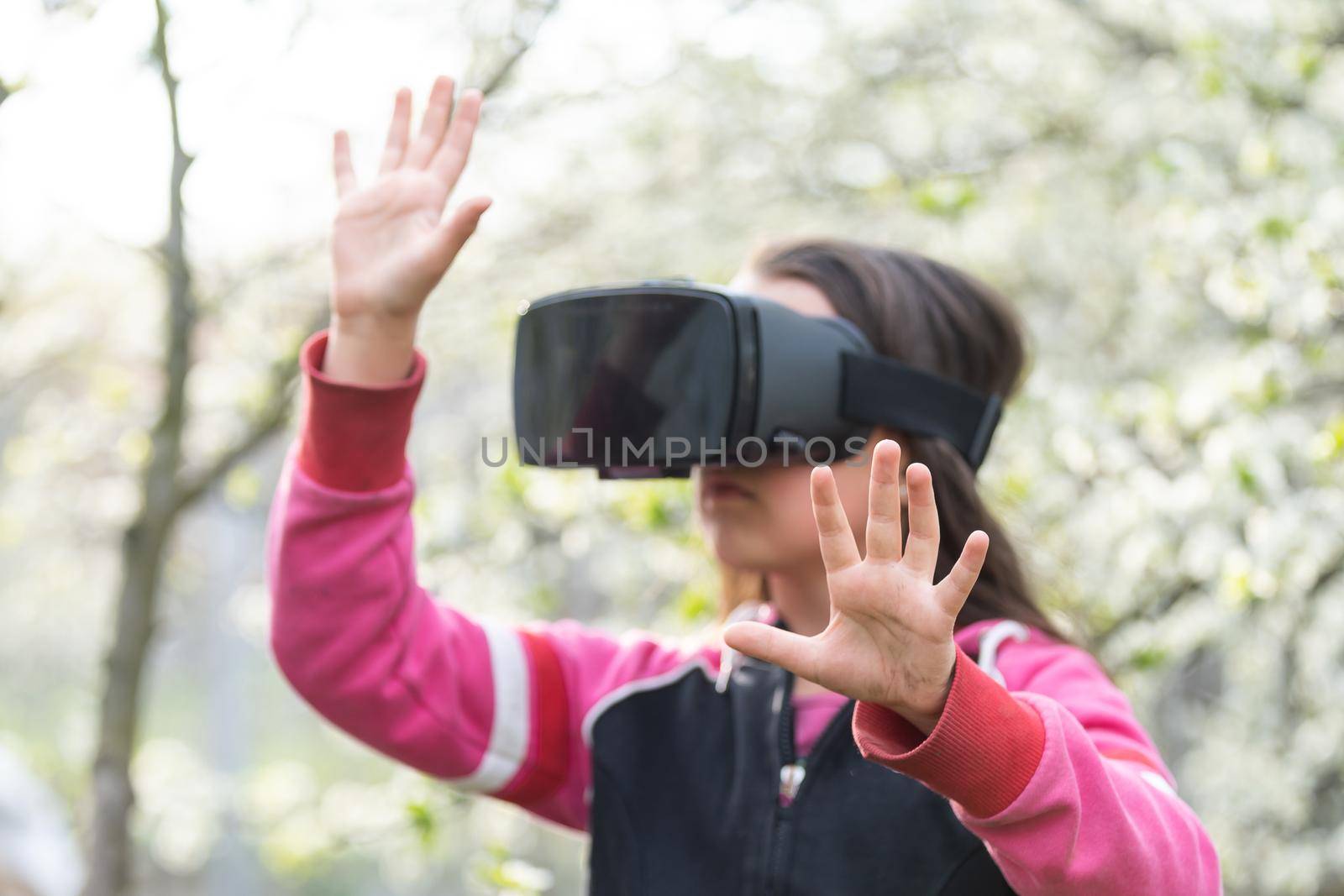 Full body little girl excited and entertained, playing with virtual reality glasses, exploring a fantasy world, trying to touch something. by Andelov13