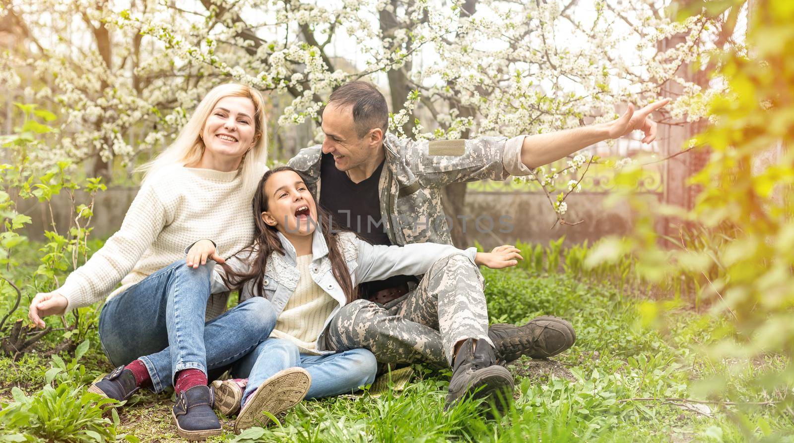 Soldier is meeting his family outdoors. Happy reunion of father and kids on the grass.