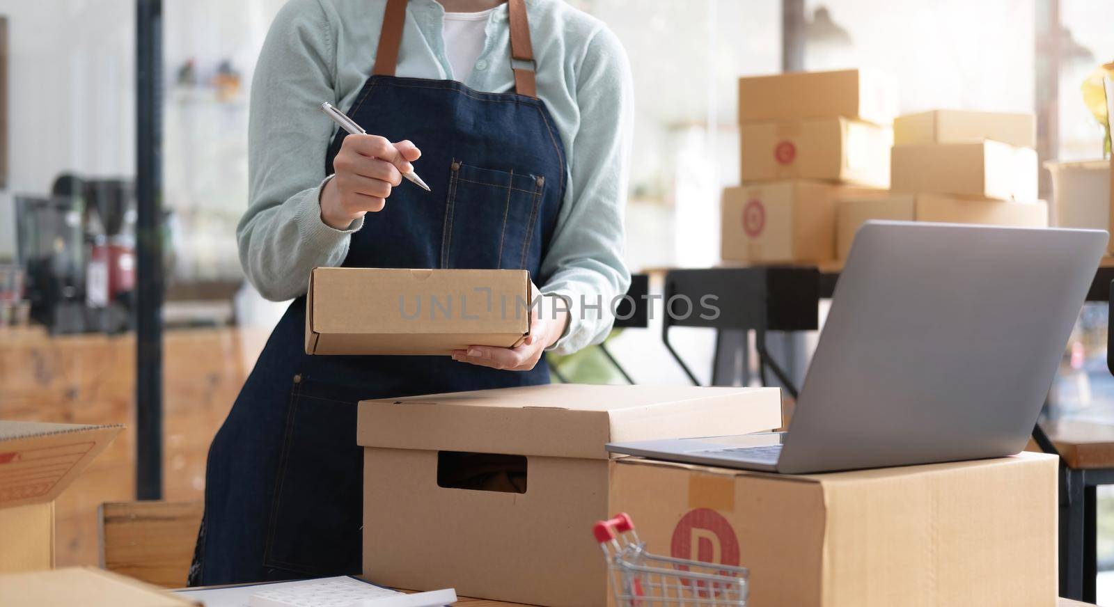 Startup Entrepreneurship Small Business SME Freelance Young lady working at home with boxes and laptop online Marketing Packaging SME Shipping Ecommerce Concepts.