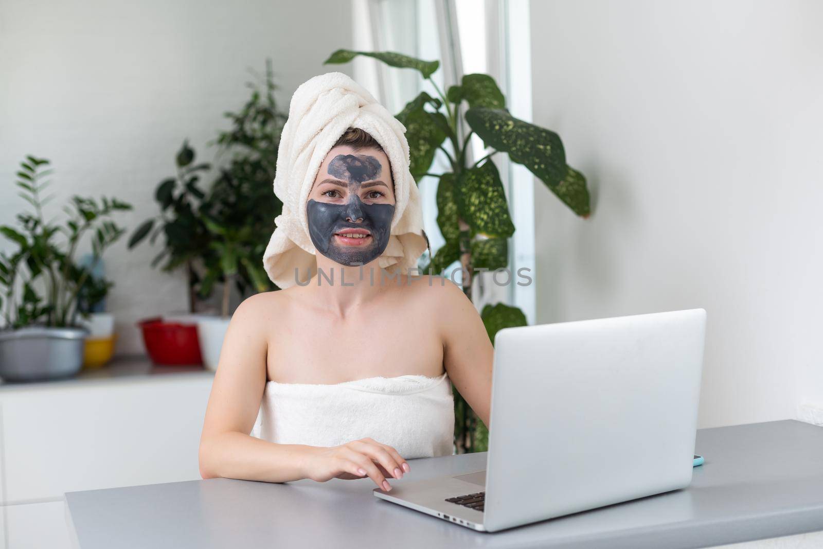 incredible pretty girl at home in pajamas made a cosmetic mask and works with a laptop. The concept of cosmetic mask on a girl. by Andelov13
