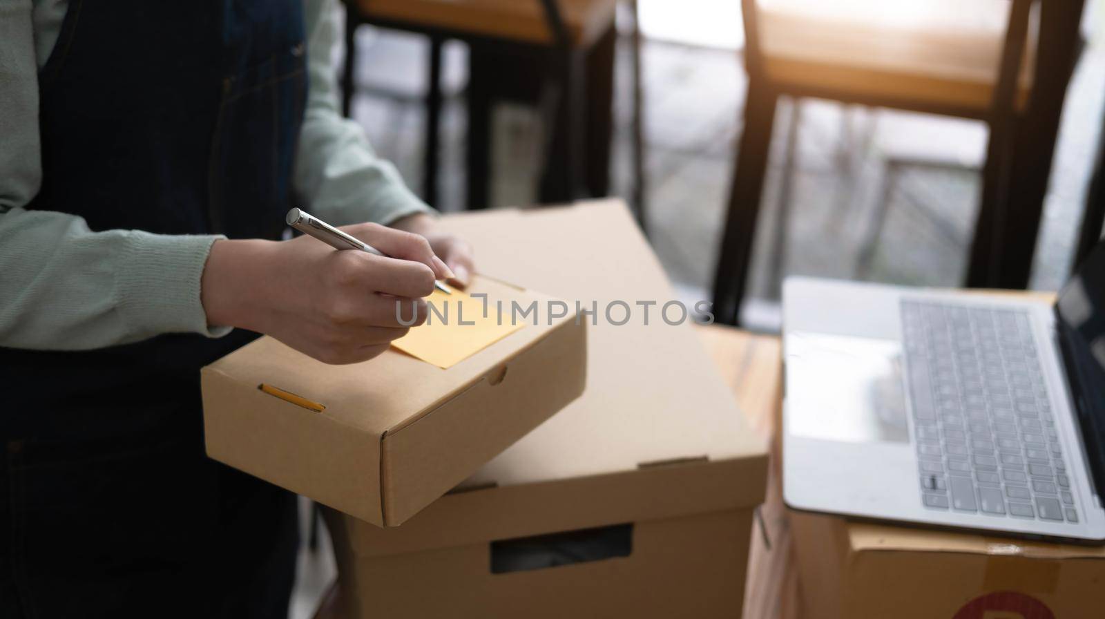 Startup Entrepreneurship Small Business SME Freelance Young lady working at home with boxes and laptop online Marketing Packaging SME Shipping Ecommerce Concepts by wichayada