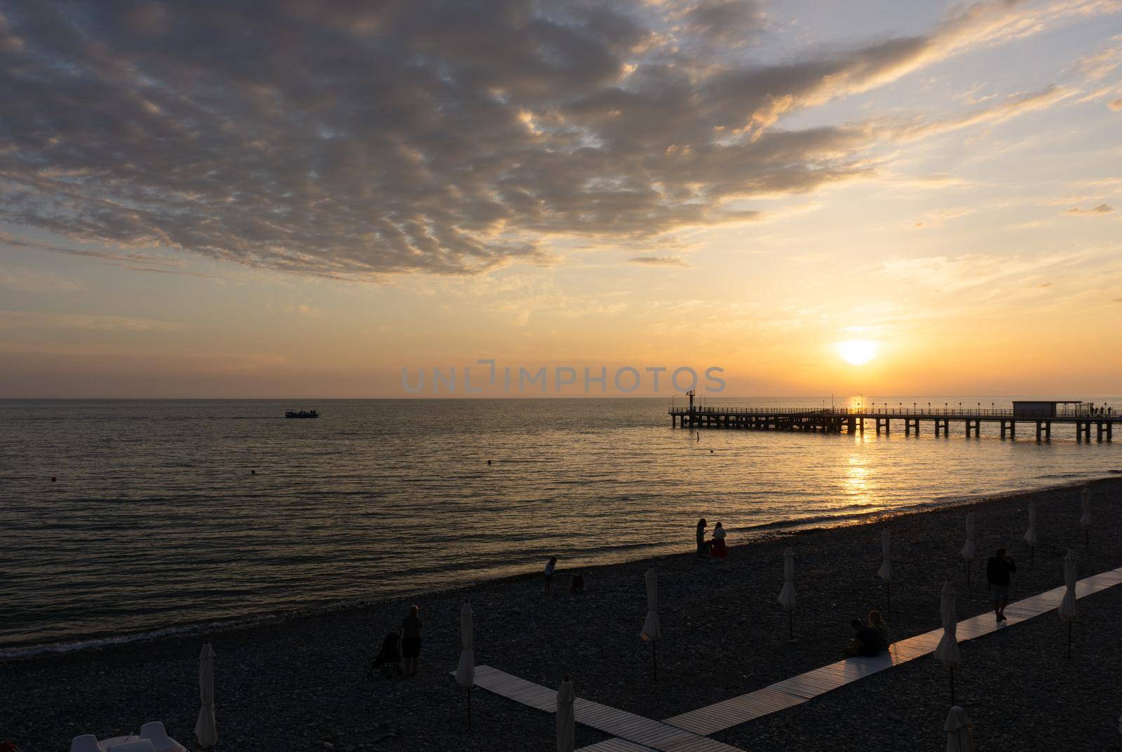 LAZAREVSKOE, SOCHI, RUSSIA - MAY, 26, 2021: Orange saturated sunset with silhouettes of people on the background of the sun.