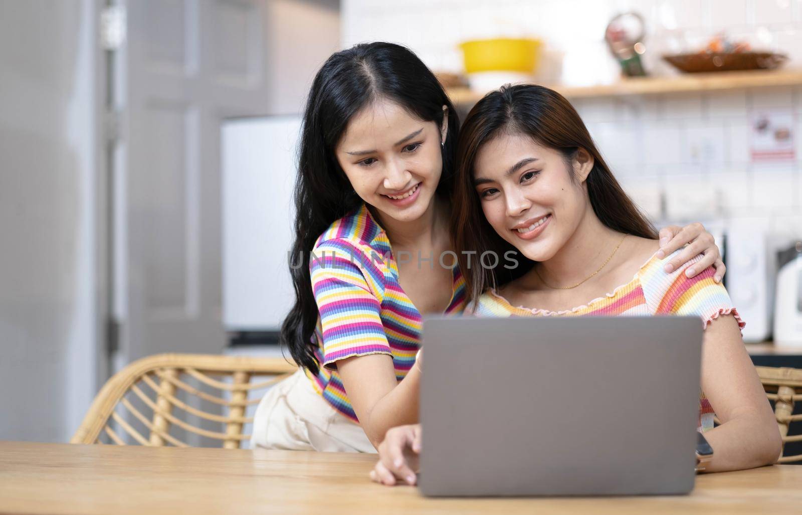 Two female LGBT lesbian couple best girlfriends hugging watching movie on laptop together