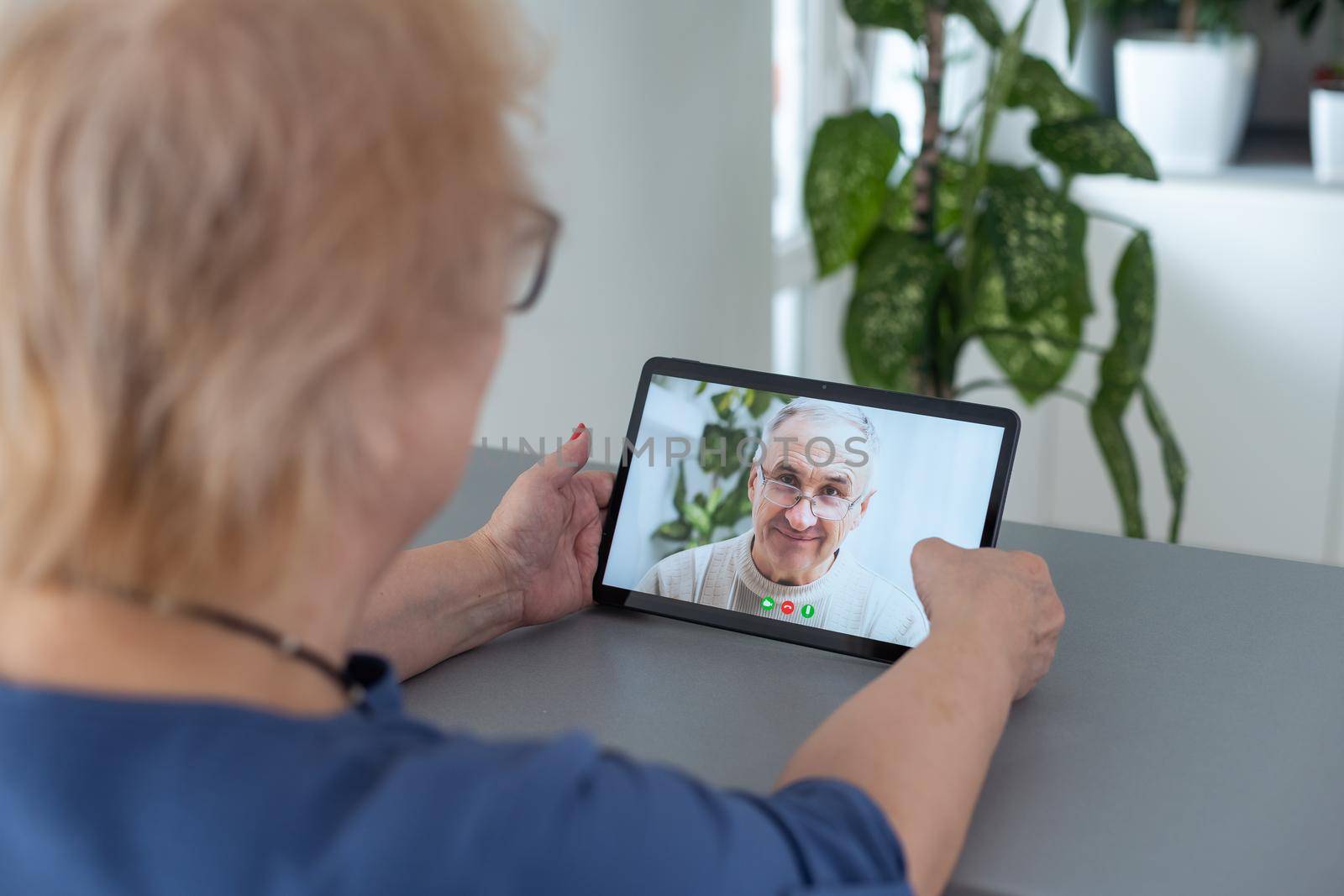 telemedicine concept, old woman with tablet pc during an online consultation with her doctor in her living room.