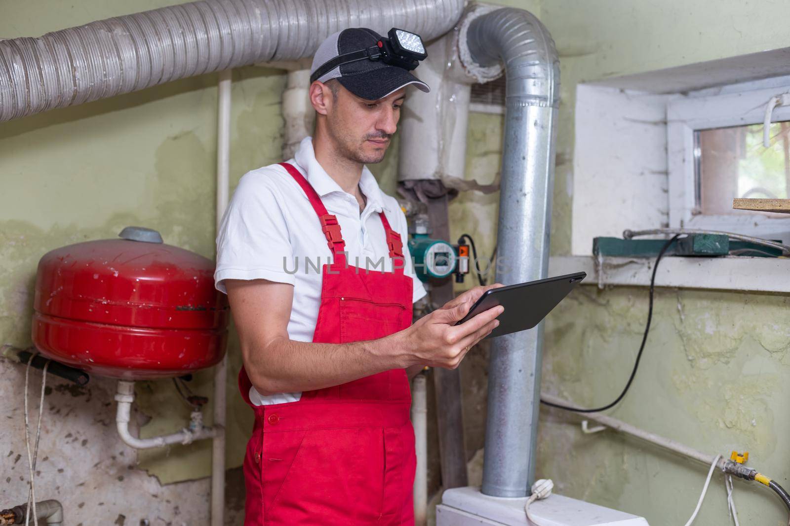 The technician checking the heating system in the boiler room with tablet in hand