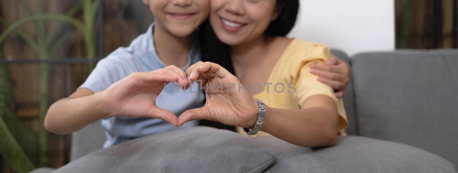 Asian mother and daughter making heart with their hands and smiling to camera. Life insurance, love and support in family relationships concept.