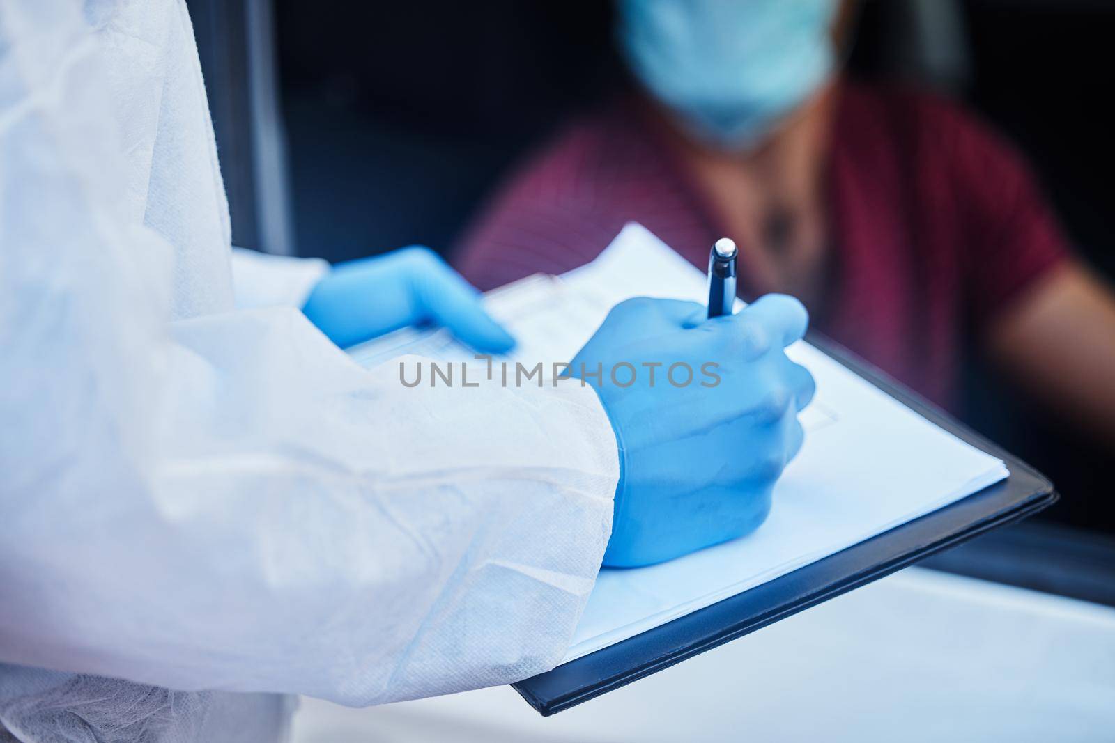 I need to record your information sir. a doctor recording a patients information for a drive through vaccination. by YuriArcurs