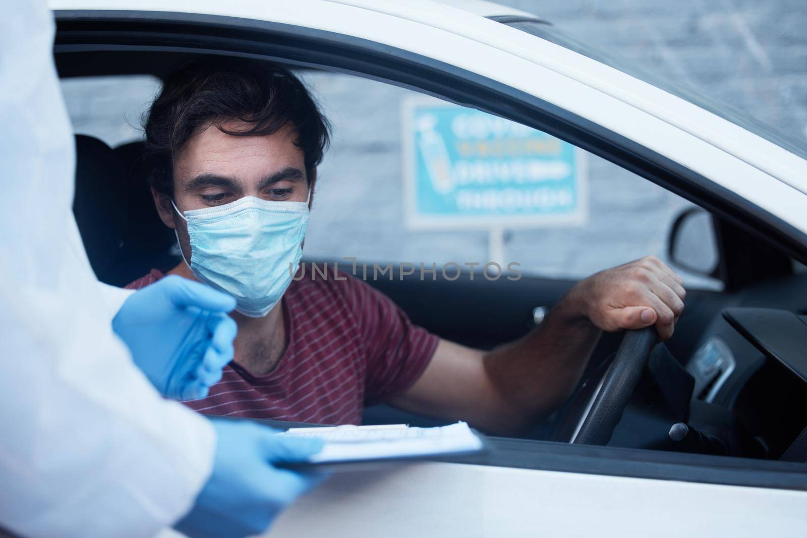 Thank you for giving me your information. a doctor recording a patients information for a drive through vaccination