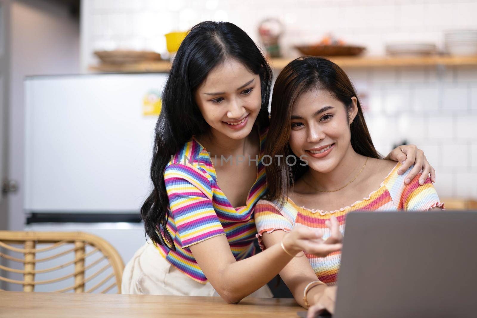 Two female LGBT lesbian couple best girlfriends hugging watching movie on laptop together. by wichayada