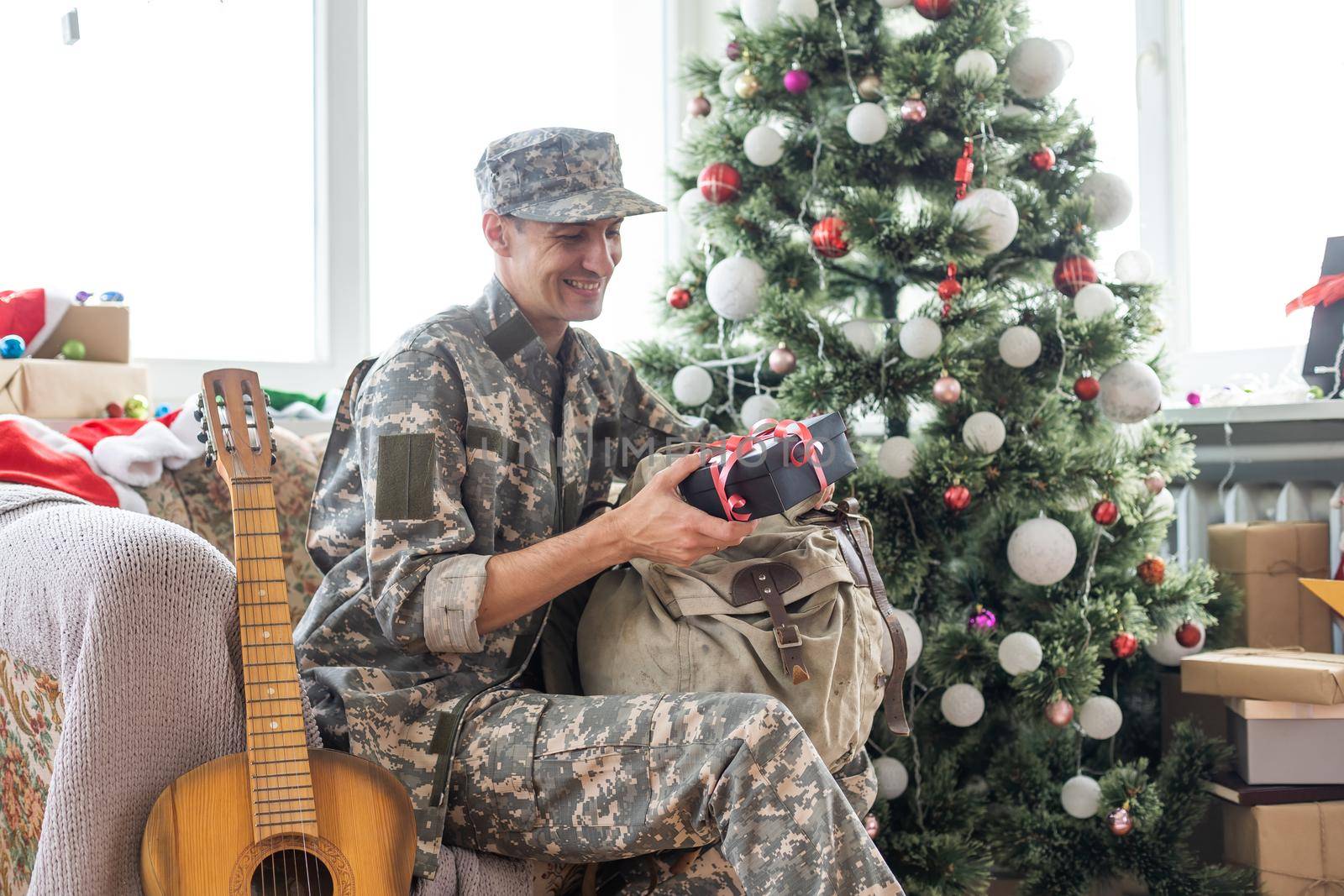 man in military uniform playing acoustic guitar at home at christmas by Andelov13