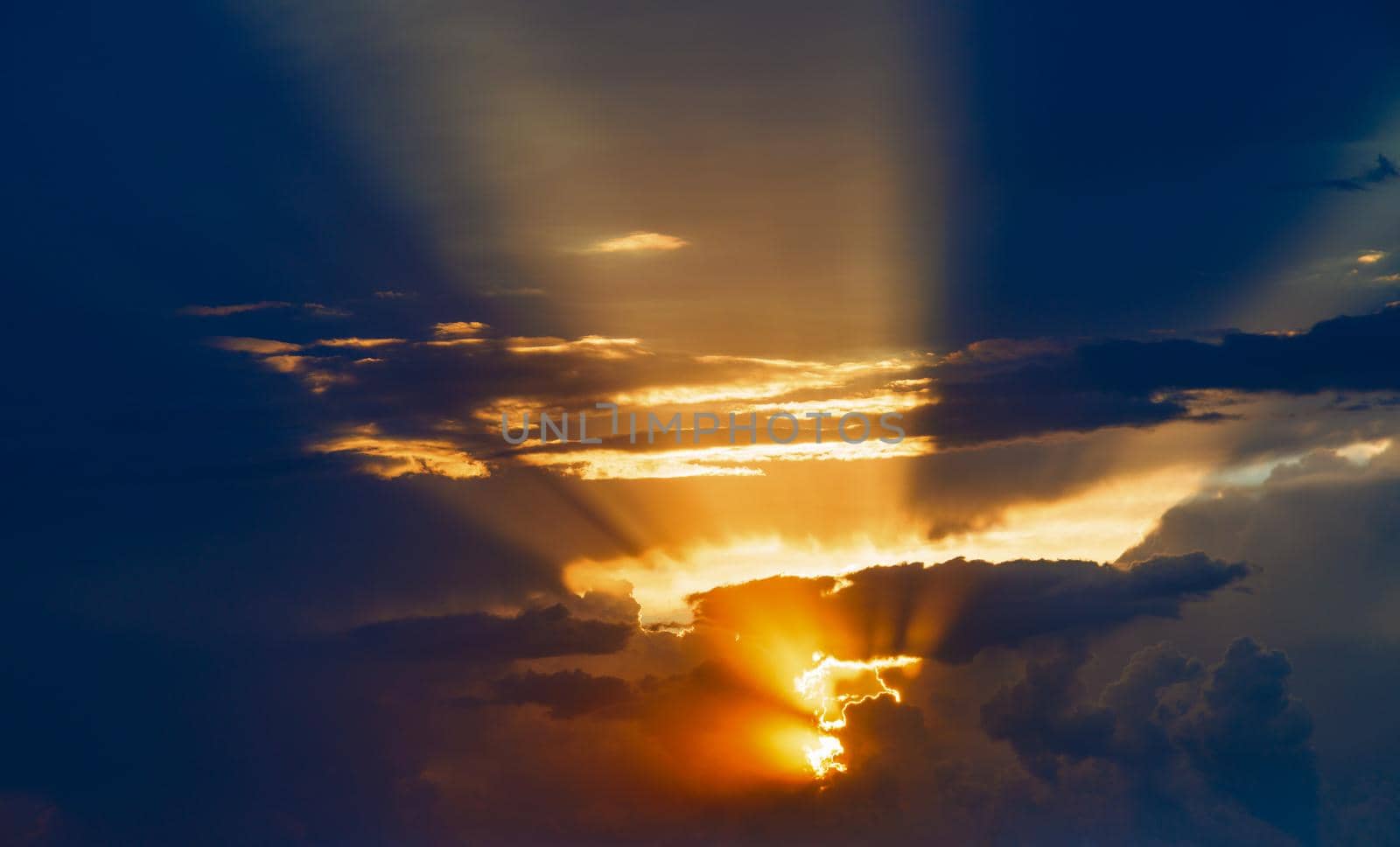 cloudy sunset sky with yellow sun rays without horizon, captured with 100mm lens