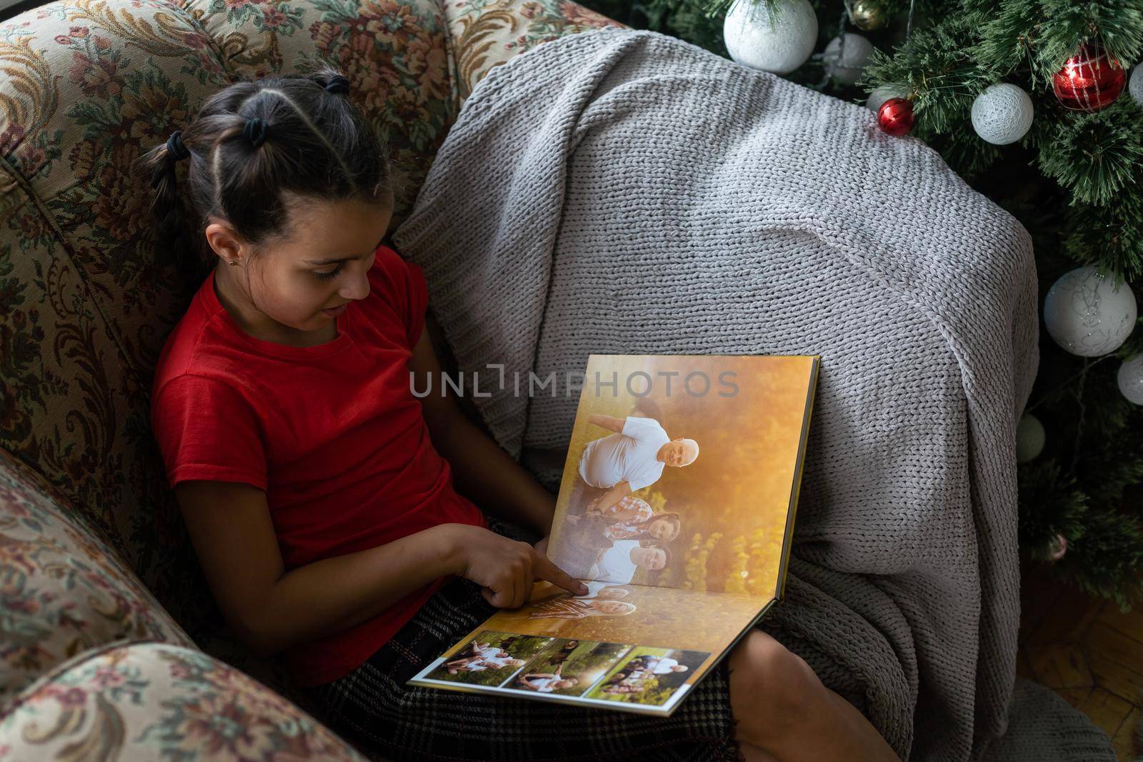 a little girl looking at a photo album in the living room.