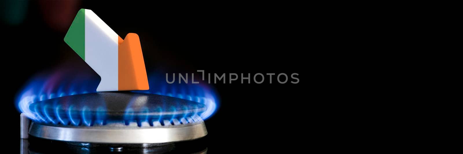 Decreased gas supplies in Ireland. A gas stove with a burning flame and an arrow in the colors of the Ireland flag pointing down. Concept of crisis in winter and lack of natural gas. Heating season. by SERSOL