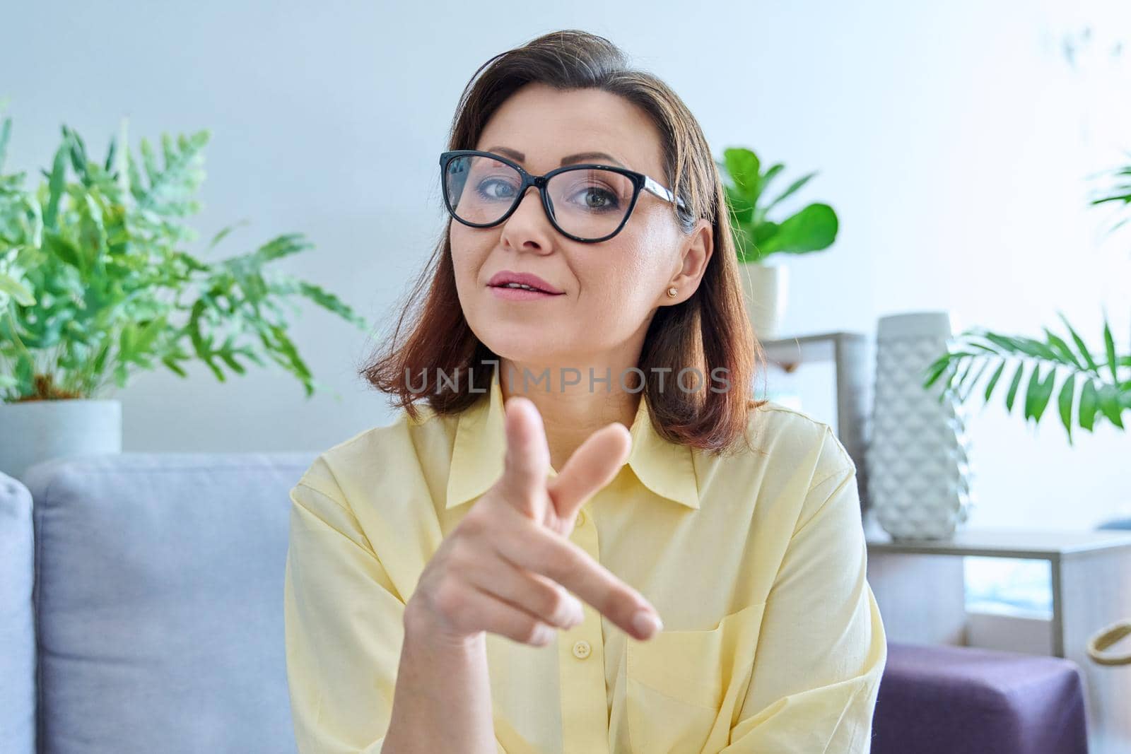 Headshot portrait of middle aged woman looking at webcam. 40s confident business female talking, making video call conference chat, sitting on couch in home office. Work technology age people concept