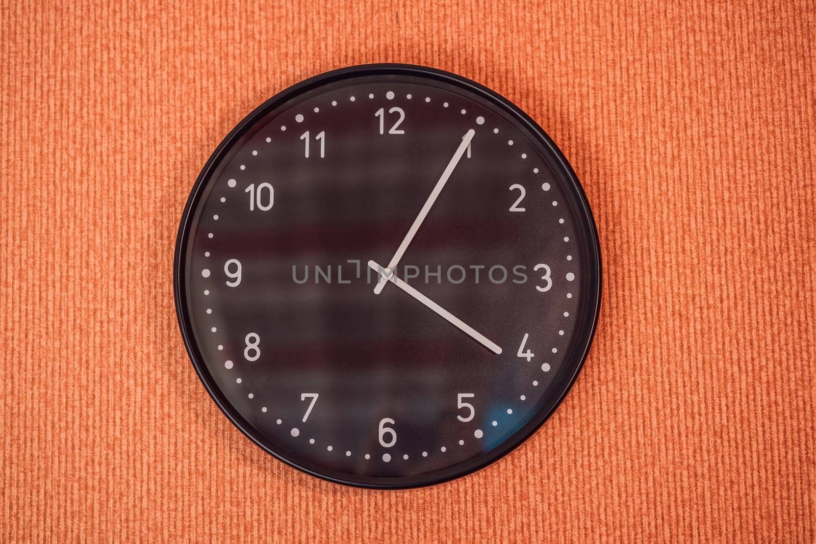 Classic black and white analog clock on red background at One o'clock with copy space.