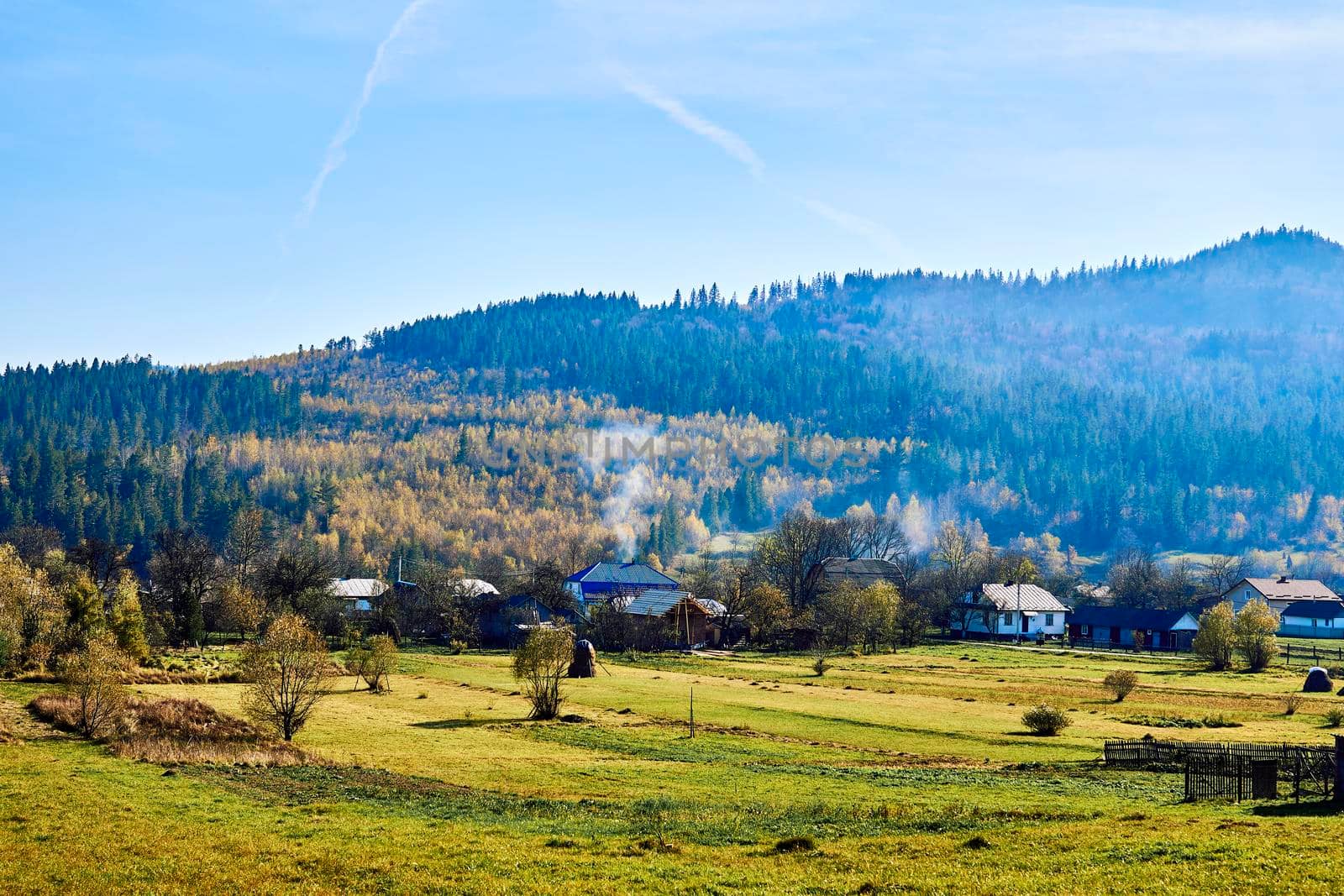 Mountain range and village in autumn colors and blue sky by jovani68