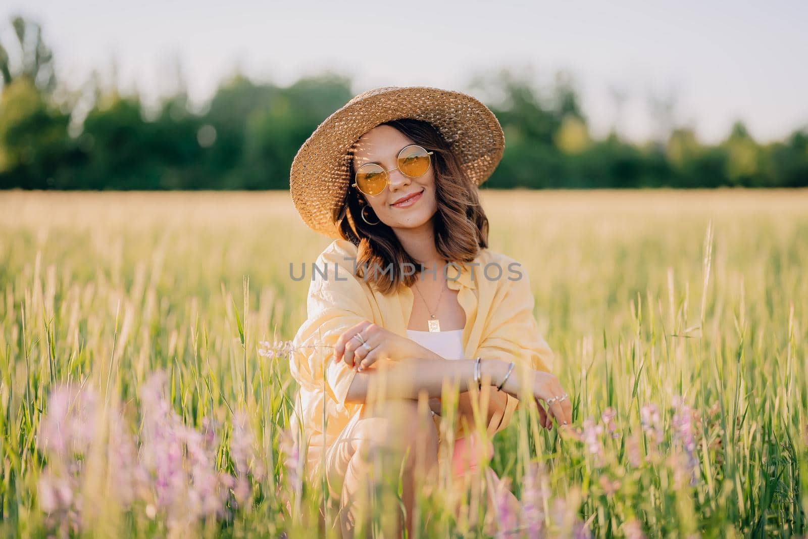 Portrait of rural stylish woman in straw hat posing in fresh wheat field. Grass background. Amazing nature, lifestyle, farmland, growing cereal plants. by kristina_kokhanova