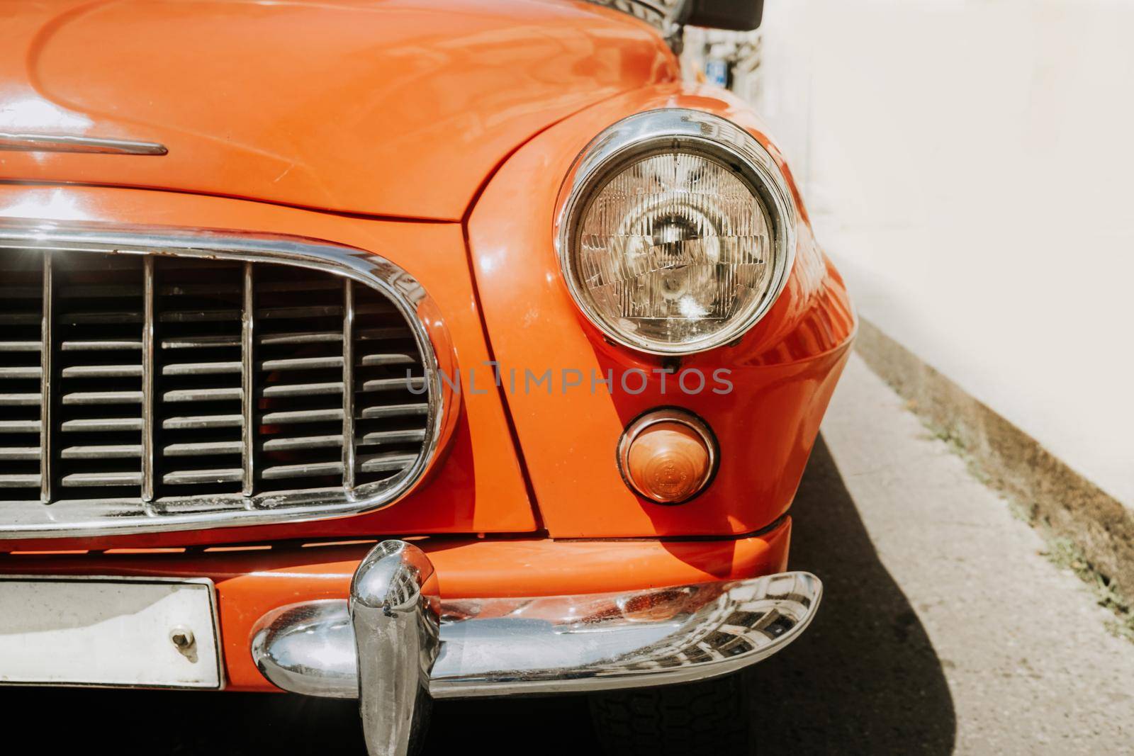 Detail of retro automobile brand, headlight close-up view. Orange roadster. Symbol of vintage car maker and producer. High quality photo
