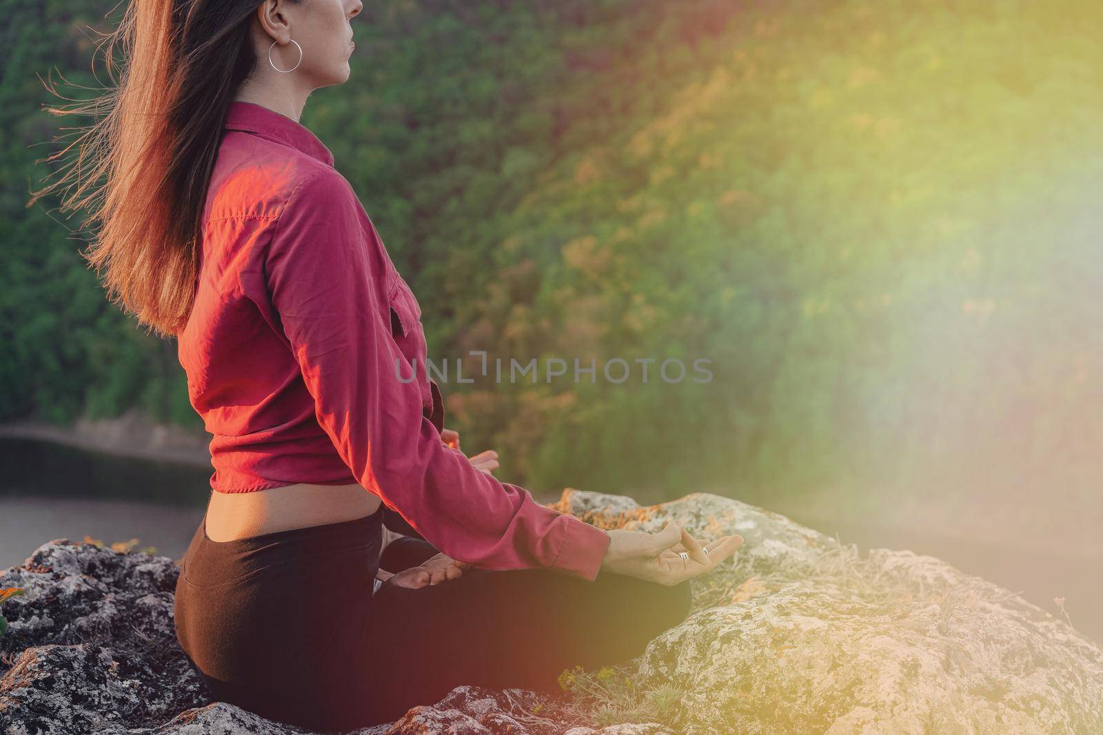 Peaceful yogi woman sitting in lotus, meditating, feeling free in front of wild nature. Mindful fitness coach having zen moment. Everyday yoga practice, calm breath, concentration concept.High quality
