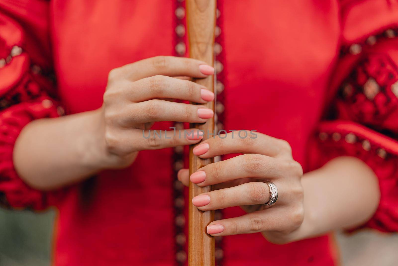 Woman playing woodwind wooden flute - ukrainian sopilka outdoors. Folk music concept. Musical instrument. Lady in traditional embroidered shirt - red Vyshyvanka. High quality photo