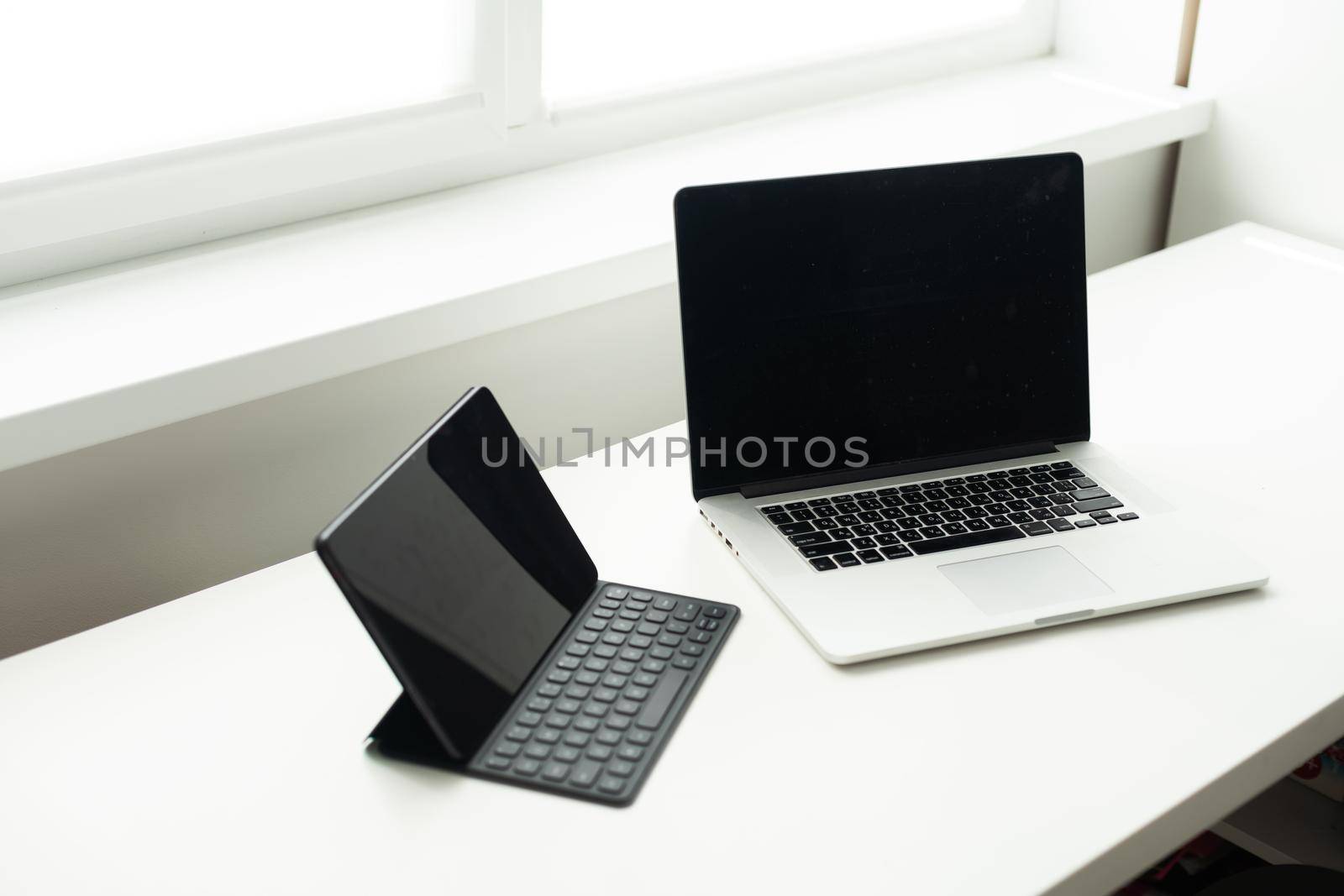 laptop and tablet on a white table.