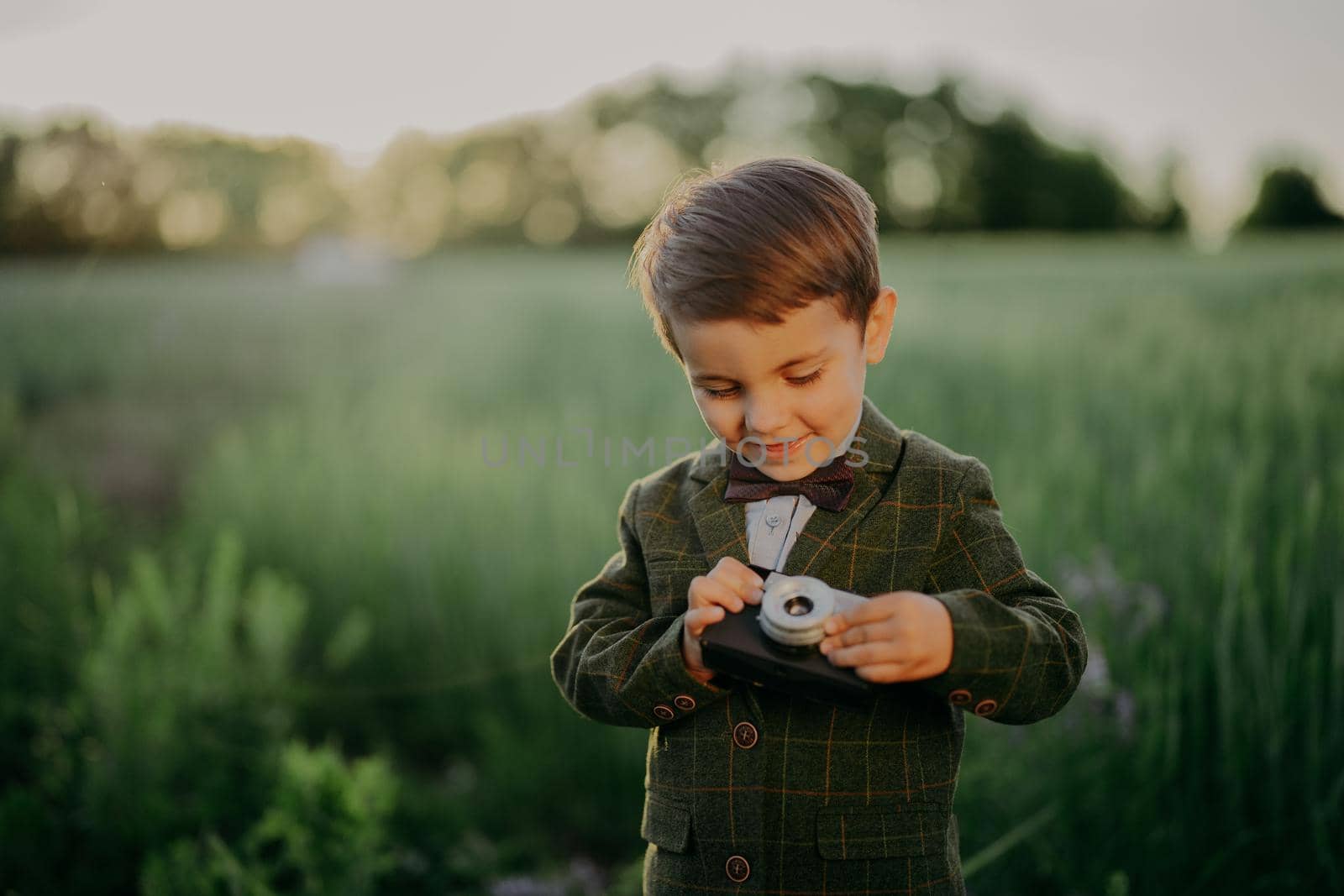 Handsome little boy with vintage retro camera. Kid as young photographer studying to take pictures. Hipster festive costume. Child, son, hobby, holiday concept. High quality photo