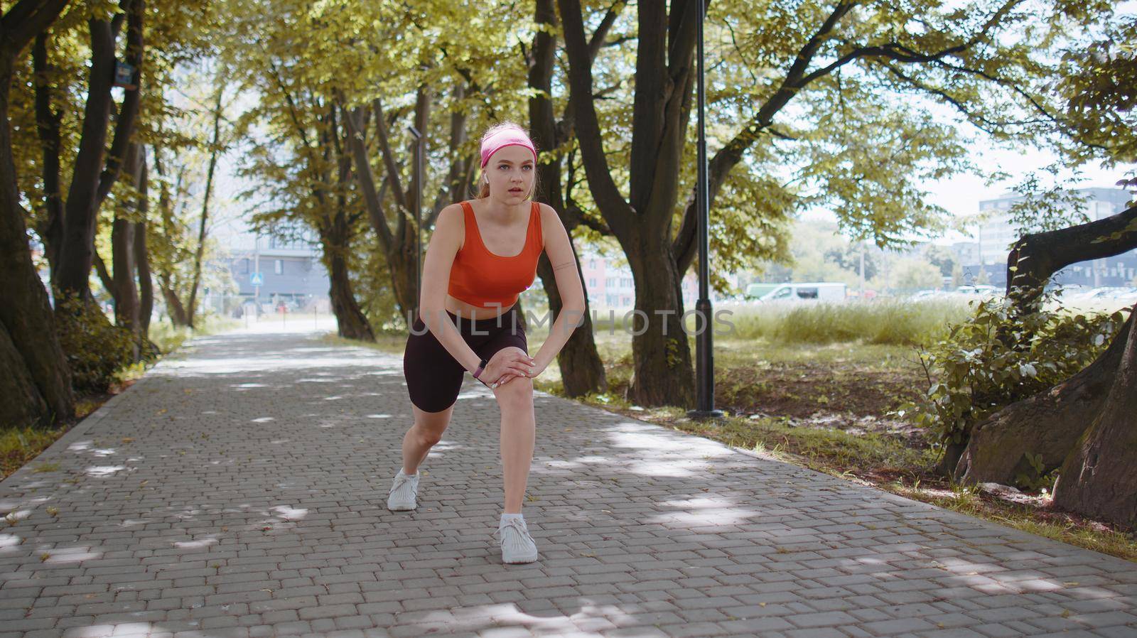 Athletic fit sport motivated runner girl training, preparing to run race marathon. Workout cardio in morning sunny park. Young woman jogger enjoying healthy lifestyle. Active sportswoman motivation