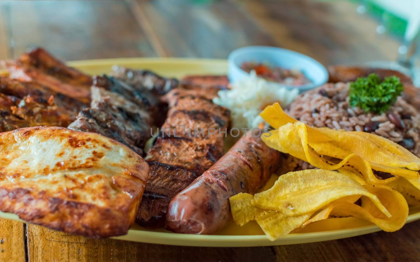 Variety of fried and grilled meats served on wooden table. Traditional Nicaraguan bay horse served on the table. Variety of food meats and assortment of sausages