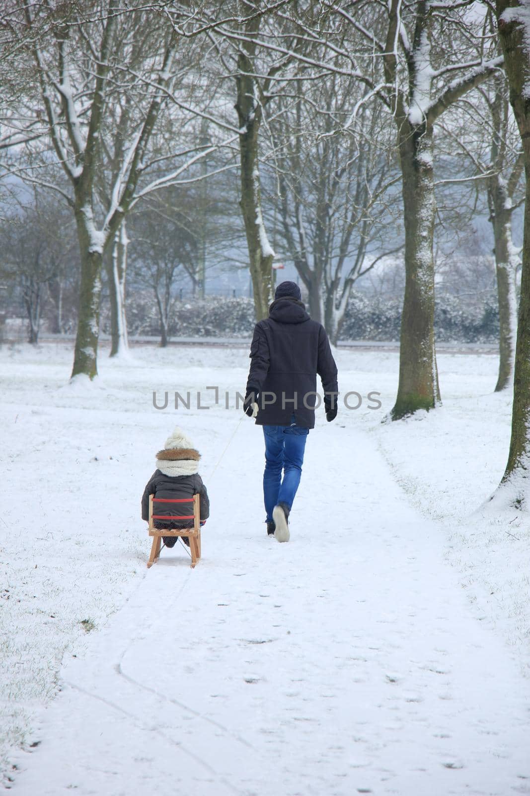 Father and son walking in the snow with a small sleigh