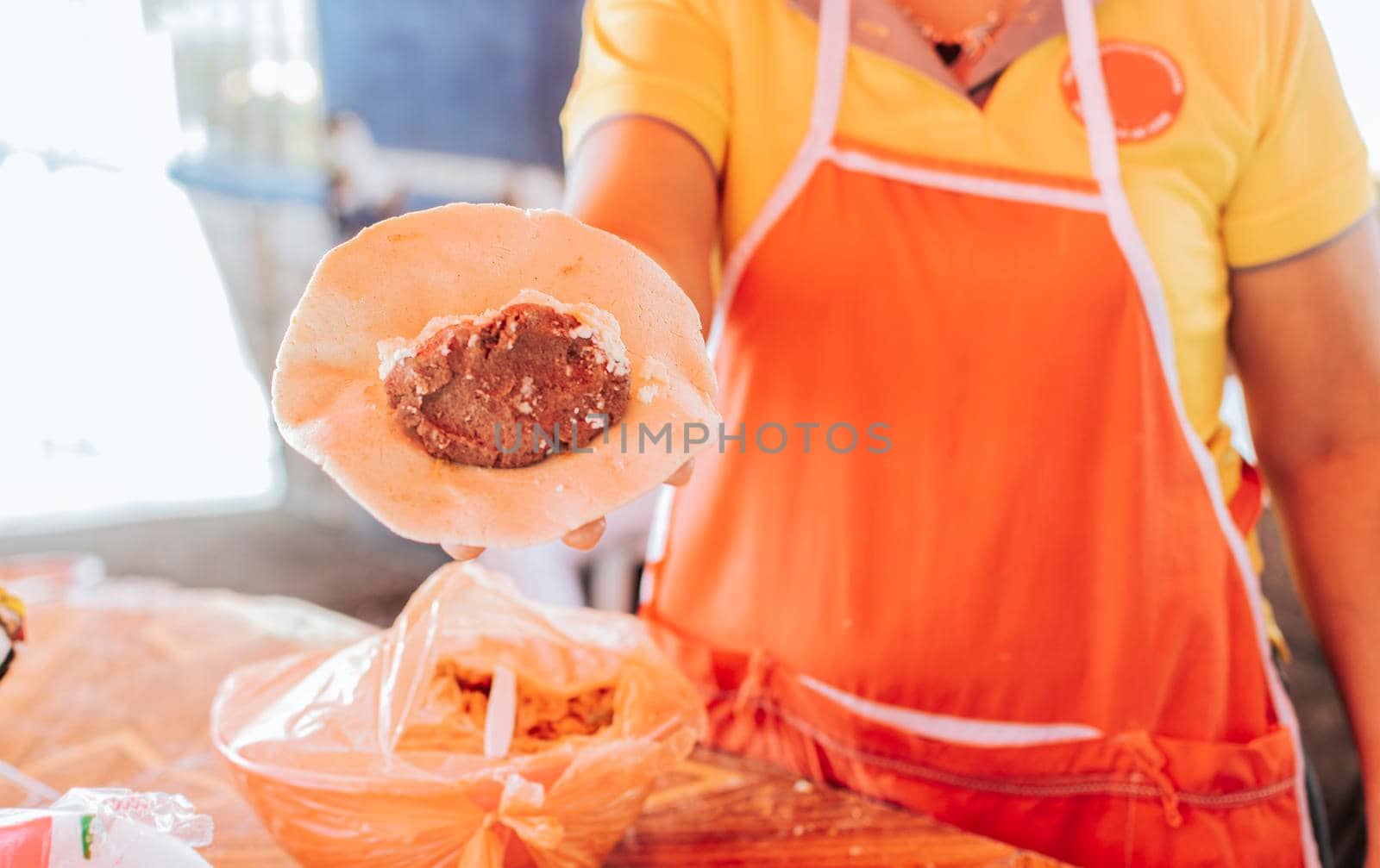 Hand of a vendor showing traditional raw pupusa. Elaboration of traditional pupusas, Preparation of the dough for traditional Nicaraguan pupusas by isaiphoto