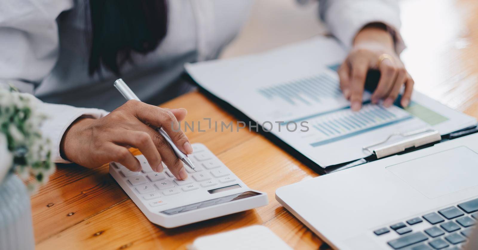 Close up hand of business woman accountant calculating budget of the company with calculator, Chart Graph Analysis.