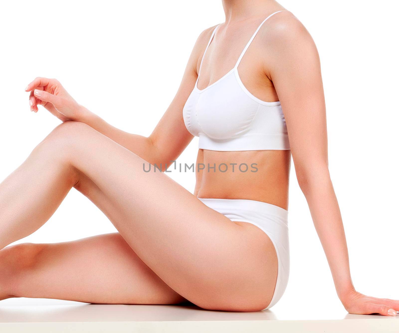 Pretty woman with slim beautiful body sitting against white background, isolated