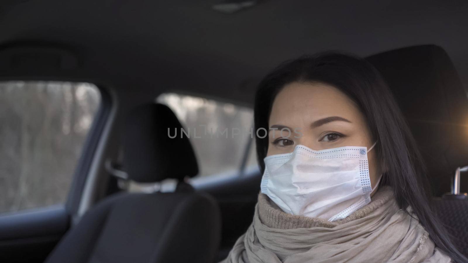 Doctor In Mask Looks At Camera Sitting In Car by LipikStockMedia