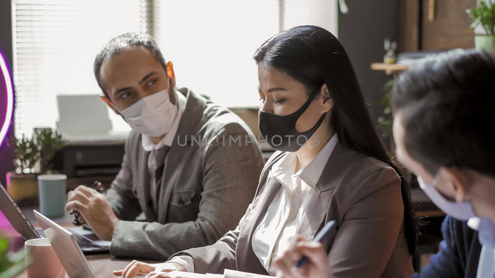 Teamwork Of Business People During Virus Outbreak, Colleagues In Protective Masks Working In Office, Selective Focus On Beauty Asian Woman Using Laptop