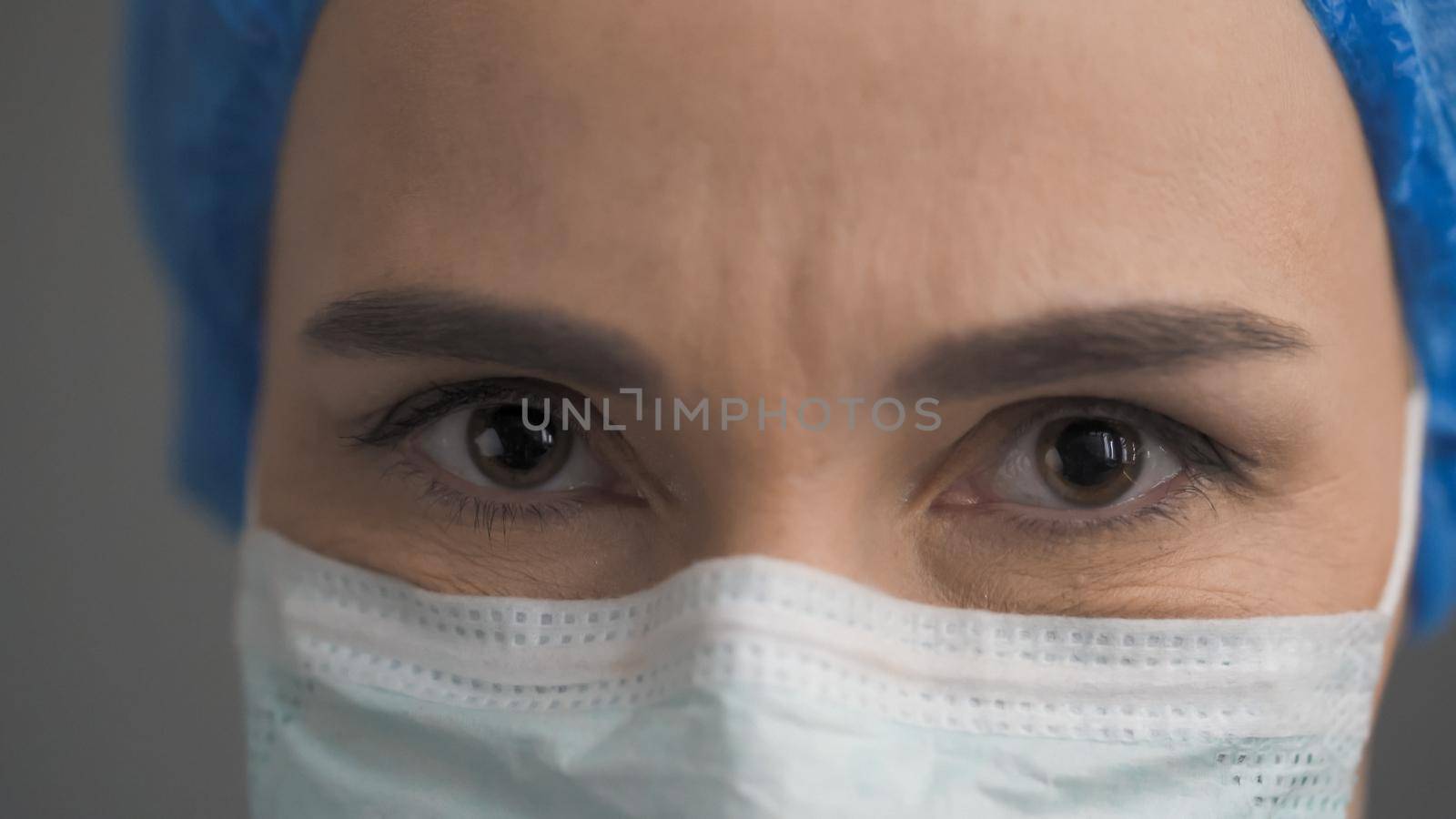 Medic In Protective Mask And Blue Cap Looking At Camera, Portrait Of Female Doctor Working During Coronavirus Or Covid-19 Virus Epidemic, Close Up Of Doctor's Eyes, Front View