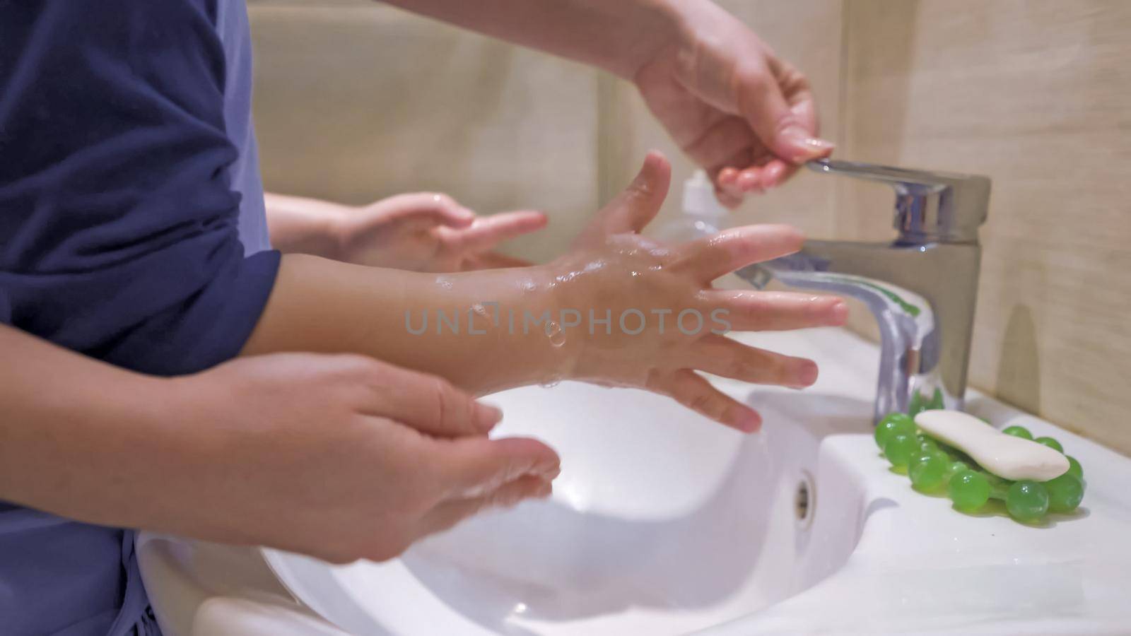 Mother With Son Washing Hands Together by LipikStockMedia