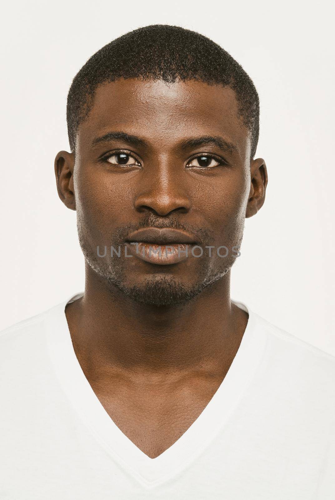 Attractive African american man looking seriously at the camera, Dark-skinned guy in a white t-shirt on a white background looks confident, cut out on white. Toned image by LipikStockMedia