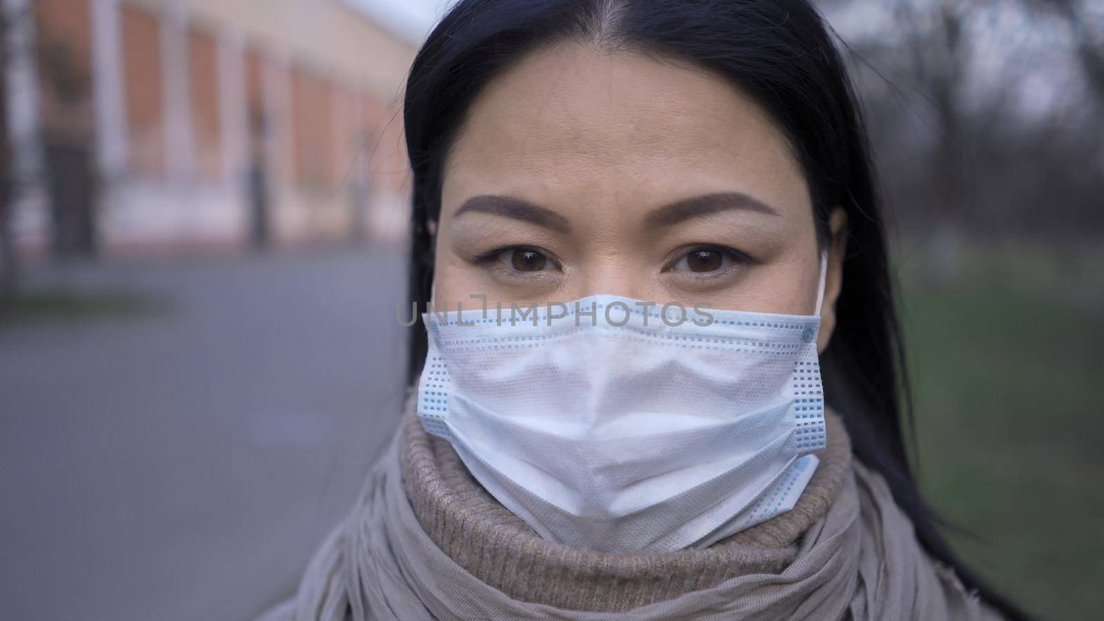 Asian woman in mask standing outdoors, close up by LipikStockMedia