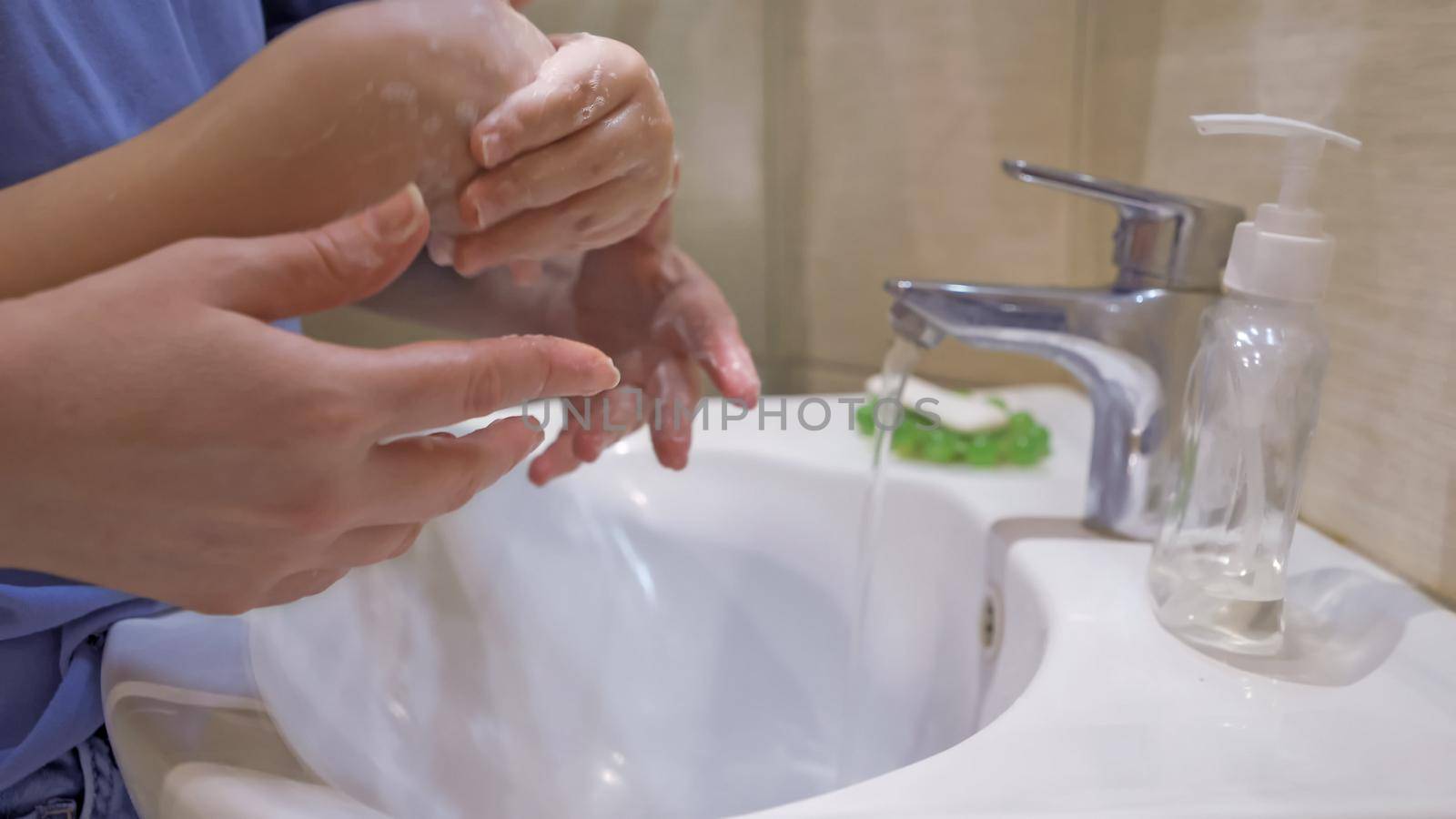 Boy Washing Hands With Mom Together by LipikStockMedia