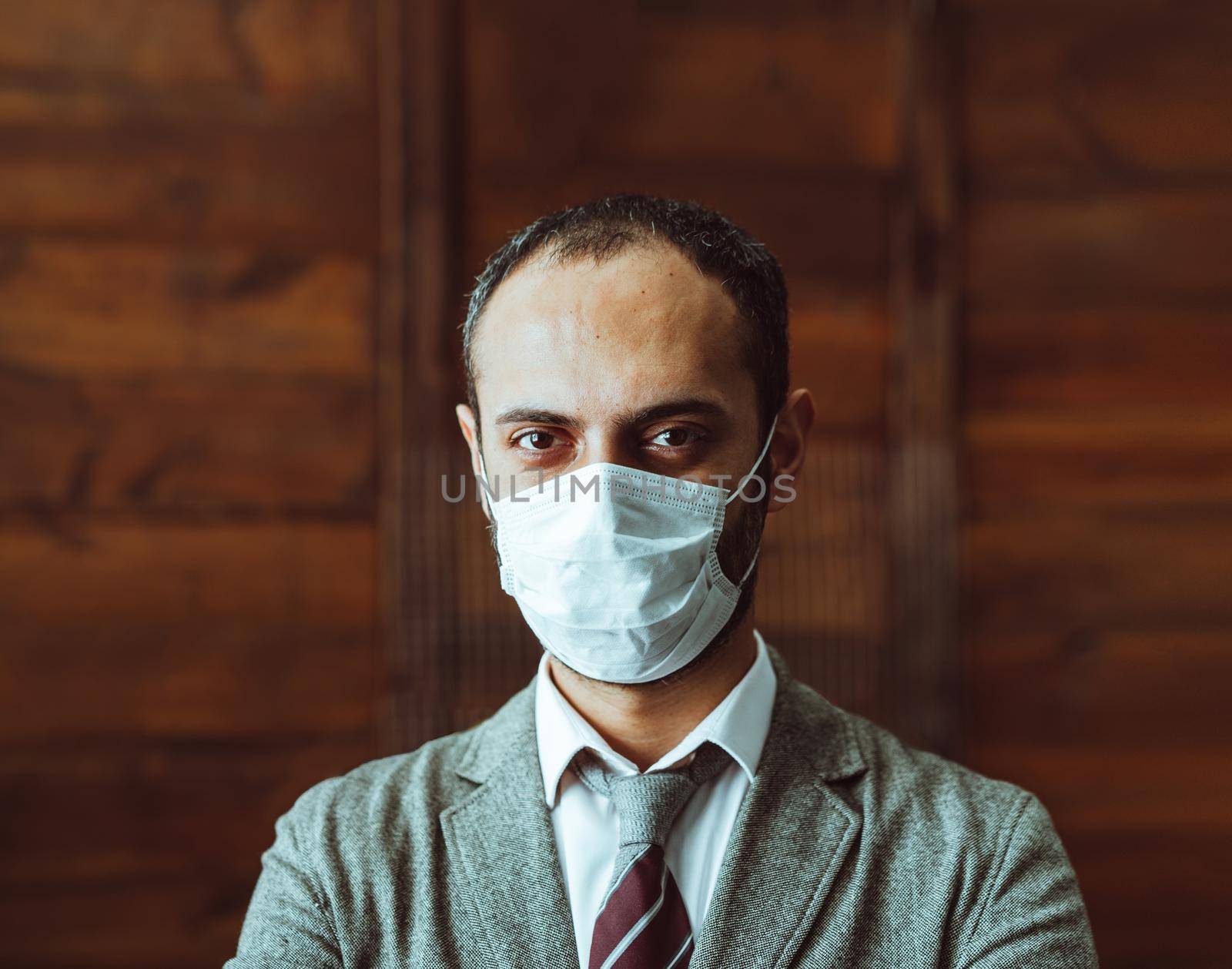 Confidence Man In Protective Mask Stand Alone In Office by LipikStockMedia