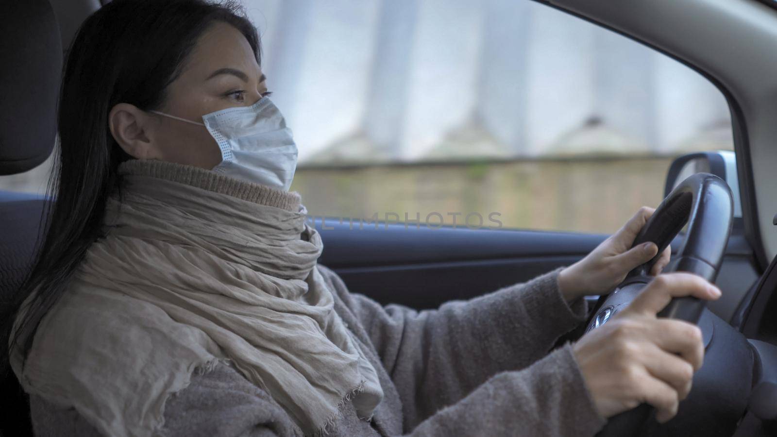 Woman In Mask Holds Steering Wheel Driving Car, Asian Woman Driving Car As Taxi Driver Wearing Protective Mask Trying To Earn Money For Family During Quarantine Coronavirus Days